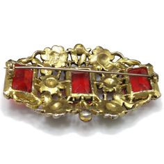 *Description: This is a beautiful floral Art Nouveau emerald cut red glass brooch with gold flowers on a wide brooch from the 1930s to 1940s. The gold flowers flow between the six red rhinestone chatons and three evenly placed large emerald cut red glass rhinestones. There is an early rolling c clasp and long pin on the back reaching from one side to the other. The large stones are open back, allowing the light to shine through. The metal is gold toned pot metal. This would be a great addition t Red Rhinestone, Emerald Cut, Red Glass, Gold Flowers, Floral Art, Emerald, Art Nouveau, Gold Tones, Vintage Jewelry