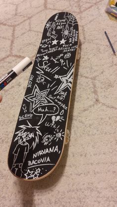 a skateboard with writing on it sitting on the floor next to markers and pens