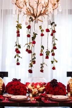 the table is set with red roses and place settings for two people to sit at