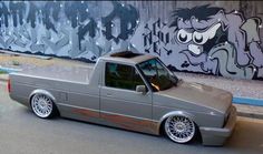 a gray truck parked in front of a graffiti covered wall