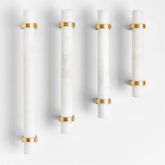 four white and gold candles are lined up against the wall