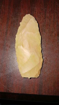 a piece of yellow paper sitting on top of a wooden table next to a knife