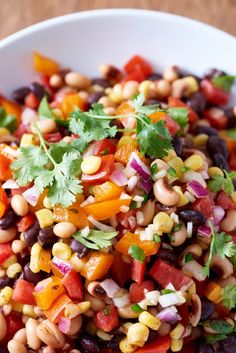 a white bowl filled with beans and veggies on top of a wooden table