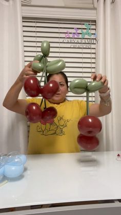 a woman is holding up balloons in front of her face and hands, with the balloon flowers attached to them