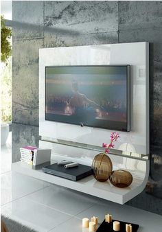 a flat screen tv sitting on top of a white shelf next to a vase with flowers