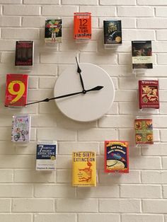 a clock made out of books and magnets on a brick wall with white bricks