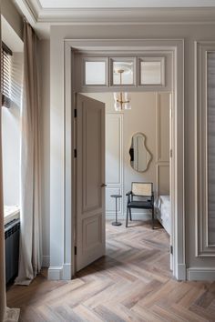 an open door leading to a bedroom with a chair and mirror on the wall next to it