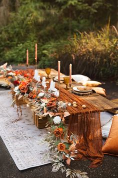 a long table is set with candles and flowers on it, along with other place settings