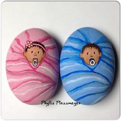 two painted rocks with faces on them sitting next to each other in front of a white background