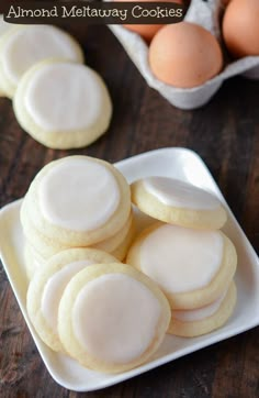 cookies with white frosting on a plate next to eggs