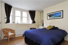 a bed room with a neatly made bed and a chair next to the window in it