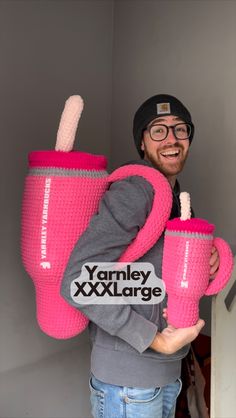 a man holding two large pink cups in his hands