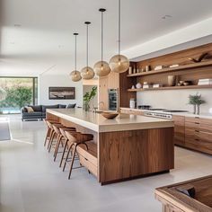 an open kitchen with wooden cabinets and hanging lights above the countertop, along with bar stools