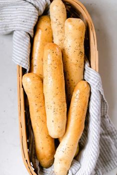 a basket filled with hot dogs on top of a white counter next to a towel