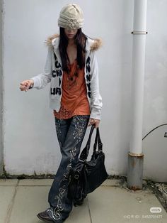 a woman is standing on the sidewalk holding a handbag