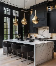 a kitchen with marble counter tops and gold pendant lights hanging from the ceiling over the island