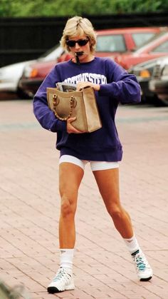 a woman is walking down the street talking on her cell phone and holding a purse