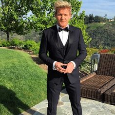 a man in a tuxedo standing on a stone slab