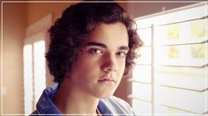 a young man with curly hair looking out the window