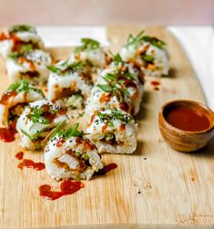 some food is laying on a cutting board with sauce and ketchup in the background