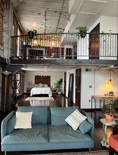 a living room filled with furniture next to a loft style bedroom on top of a wooden floor