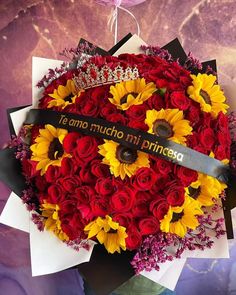 a bouquet of sunflowers and red roses with a tiara on the top