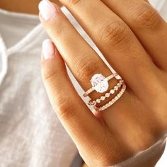 a woman's hand with a ring on top of her finger and an engagement band in the middle