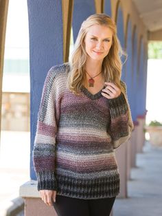 a woman standing on the sidewalk wearing a sweater and leggings with her hands in her pockets