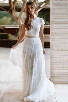 a woman in a white dress is standing outside