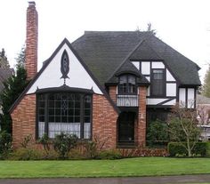 a large brick house with black and white trim on the windows, along with green grass