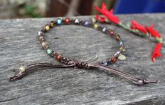 two bracelets with different colored beads are sitting on a piece of wood