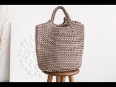 a crocheted bag sitting on top of a wooden stool next to a white wall