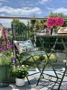 a chair and table on a balcony with flowers in the potted planter next to it