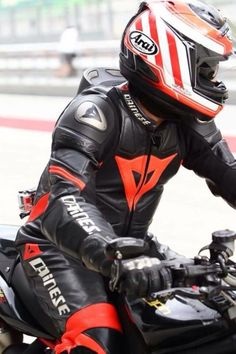 a man riding on the back of a motorcycle down a race track in leathers