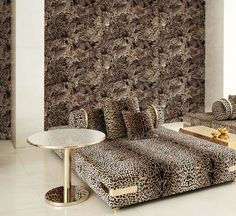 a living room with leopard print couches and tables in front of a wallpapered background