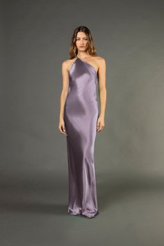 a woman in a long purple dress with one shoulder and an asymmetrical neckline