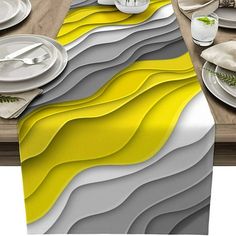 the table is set with plates, silverware and napkins in yellow and grey