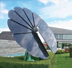 a large satellite dish sitting in the middle of a lush green field next to a house