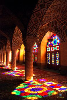 the sun is shining through stained glass windows in an ornate building with columns and arches