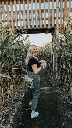 a woman standing in the middle of a corn field