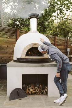 a man standing in front of an outdoor pizza oven