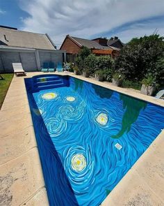 an outdoor pool with blue water and white clouds painted on the bottom, in front of a house