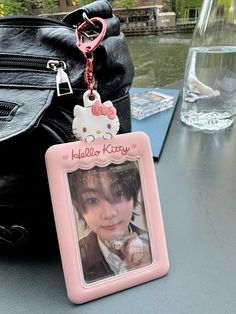 a hello kitty keychain hanging from a table next to a purse and water