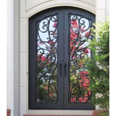 a black double door with decorative iron work on the sides and side panels that lead into a garden