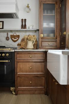 a kitchen with wooden cabinets and marble counter tops, black stove top oven and white sink