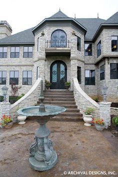 a large stone house with a fountain in the front yard