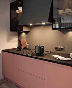 a kitchen with pink cabinets and black counter tops is lit by recessed lights above the stove