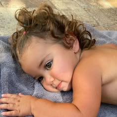 a small child laying on top of a blue towel