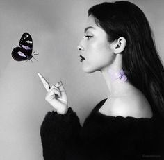 a black and white photo of a woman with a butterfly on her finger