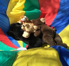 two stuffed animals laying on top of a rainbow colored blanket